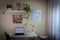 desk with laptop and chair in front, shelves with plants and on the right a window with a white curtain, home office, sunbeams