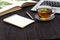 Desk with laptop, eyeglasses and a cup of tea on a wooden table