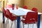 Desk of a nursery school with pencils and small red chairs