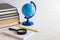 Desktop with books, notebook, globe, pen and magnifying glass. Copy space, selective focus. Education and business