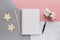 Desktop items with paper blank, pen, straw, wooden stars, cotton flower on tricolour background. Top view, flat lay, overhead,