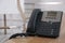 Desktop telephone on wooden table in office, space for text. Hotline service