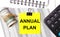 On the desktop there are reports, notepads, a calculator, a cash and a yellow sticker with the text ANNUAL PLAN. Business concept