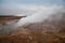 Desolate landscape of Iceland volcanic brown soil with steamy geyser mist