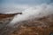 Desolate landscape of Iceland volcanic brown soil with steamy geyser mist