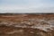 Desolate landscape of Iceland volcanic brown soil with steamy geyser mist