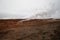 Desolate landscape of Iceland volcanic brown soil with steamy geyser mist