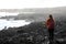 Desolate volcanic black rocks with lonely girl. Back view of young woman standing reflexive and sad on hidden rocky beach. Young