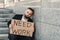 Despaired mature man holding poster Need Work while sitting outdoor on stairs near office center