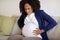 Despaired young african american pregnant woman sit on sofa suffering from contractions, screaming