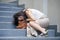Desperate Asian Japanese businesswoman crying alone sitting on street staircase suffering stress and depression crisis being