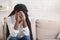 Desperate black girl sitting alone on sofa at home