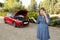 Desperate confused woman stranded with broken car engine crash accident calling on mobile phone