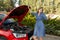 Desperate and confused woman stranded on roadside with broken car engine failure or crash accident