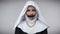 Desperate hopeless woman in nun costume with mouth closed with black tape holding hands together asking for help