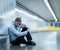 Desperate sad young businessman suffering emotional pain grief and deep depression sitting alone in tunnel subway in Stress life