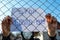 Desperate teenage boy wearing surgical mask holding a message  behind a wired fence in isolation