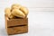 Despicable potatoes of different shapes in a wooden box on a gray background, copy space