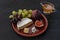 Dessert appetizers to wine - figs, brie cheese, grapes, honey served on a ceramic plate on a black background