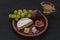 Dessert appetizers to wine - figs, brie cheese, green grapes, honey served on a ceramic plate on a black background top view close