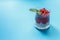 Dessert of Chia seeds and red berry jelly on a blue background, horizontal orientation with space