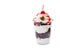 Dessert of cream, sponge cake, cherries and nuts in a plastic Cup on an isolated background.
