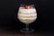 Dessert in a glass goblet. Layers laid biscuit crumbs and cream. Decorated with strawberry slices. With the addition of walnut. On