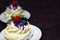 Dessert Madame Pavlova with fresh raspberries and blueberries, decorated with mint and cornflower flowers. Light dessert with