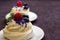 Dessert Madame Pavlova with fresh raspberries and blueberries, decorated with mint and cornflower flowers. Light dessert with