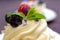 Dessert Madame Pavlova with fresh raspberries and blueberries, decorated with mint and cornflower flowers. Light dessert with