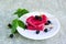 Dessert, portioned homemade ice cream or popsicles made from red currants and blackberries on a white plate on a gray concrete