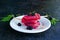 Dessert, portioned homemade ice cream or popsicles made from red currants and blackberries on a white plate on a gray concrete