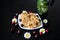 Dessert of toffee and corn sticks on a white square plate, decorated with daisies with ladybirds and cherries. Next to the kettle