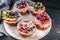 Desserts with berries: red and black currants, blueberries, raspberries, peach with almonds on a round board. Copy space