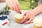 Desserts. Confectioner decorate cupcakes with cream cheese, close up. Confectioner decorating cupcake with blueberry