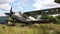 Destroyed and abandoned old plane standing in thick grass of overgrown field