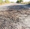 Destroyed asphalt cover on road. Bad road condition that needs repair. Theme of road construction and repair. Square format,
