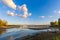 The destroyed bridge over a wide river. Autumn by the river. Beautiful cumulus clouds in a clear blue sky. Nature. Scenery