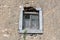 Destroyed broken old wooden window with closed window blinds on abandoned family house ruins partially overgrown with dried