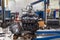 A detached engine suspended on a blue crane and a gear box on a lifting table in a vehicle repair shop. Auto industry