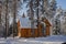 Detached two-storey log cabin, with an attic, a beautiful house painted brown, surrounded by a winter coniferous forest, covered