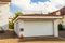 Detached white garage with orange brick tile roof