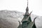 Detail of 1000 year old intricate stave church in Norway with snow-covered mountain in background