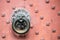 Detail of antique bronze door knocker on old red door