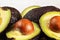 Detail of avocado halves, yellow and green pulp with dark skin - Hass / Bilse variety - pit visible in halved pears