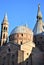 Detail of the Basilica del Santo in Padua. Sunlit near sunset spire with angel, bell tower and dome, immersed in the blue sky.