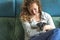 Detail of a beautiful woman with curly brown hair. Sitting on a sofa, smiling with a Jack Russel Terrier puppy in her arms