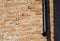 Detail of brick wall,, exterior corner of building with new drainpipe. Construction and rain sewage installation concept