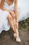 Detail of bridal legs with shoes sitting on the wooden table