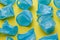 Detail of broken blue plastic disposable cups over a yellow background